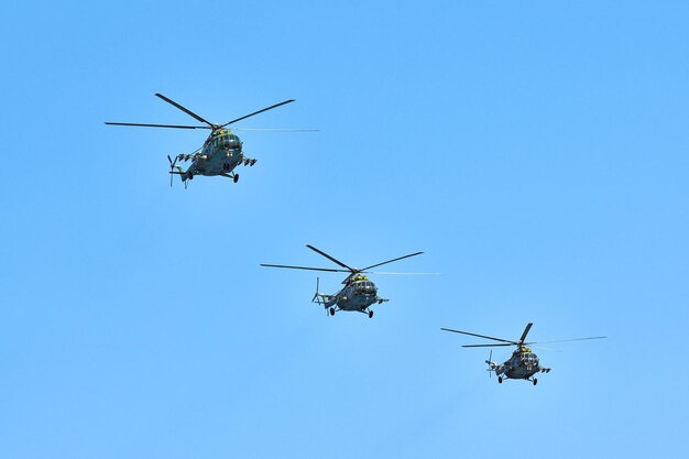 Tres helicópteros militares volando en un cielo azul brillante mientras realizan un vuelo de demostración, copie el espacio. Equipo acrobático realiza vuelo en air show