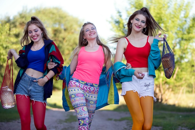 Tres hermosas chicas campesinas vestidas al estilo de los noventa caminan por la carretera