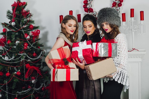 Tres hermosas chicas celebrando por el árbol de Navidad