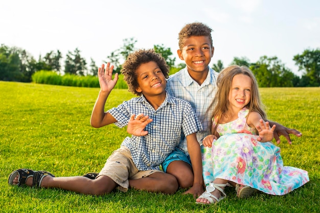 Tres hermosos niños juegan en el claro soleado con una sonrisa y se divierten.