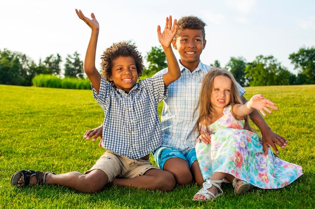 Tres hermosos niños juegan en el claro soleado con una sonrisa y se divierten