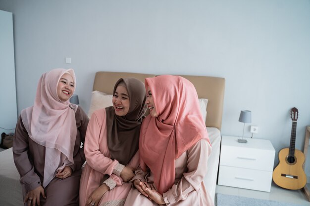 Três hijab mulher sentada na cama conversando e conversando juntos
