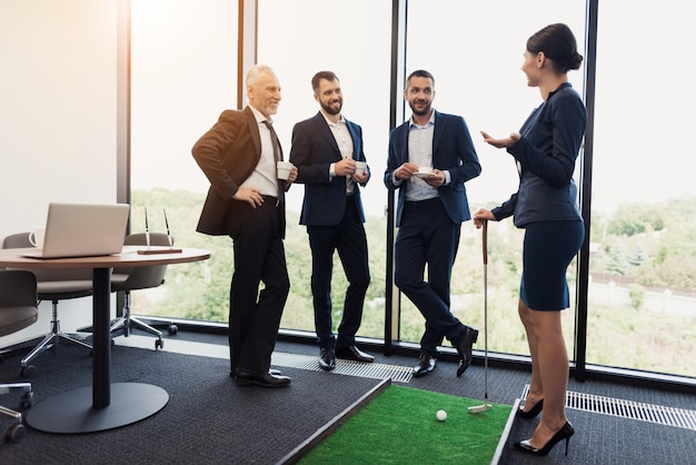 Tres hombres de negocios y mujeres de negocios juegan al golf.