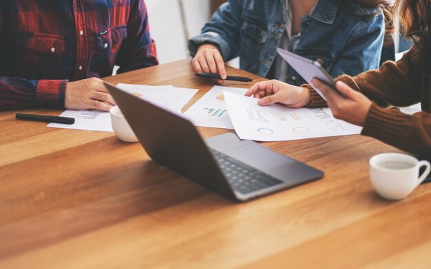 Tres hombres de negocios usando laptop y tablet pc mientras trabajan y discuten negocios juntos en una reunión