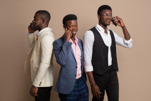 três homens africanos de terno com telefones celulares