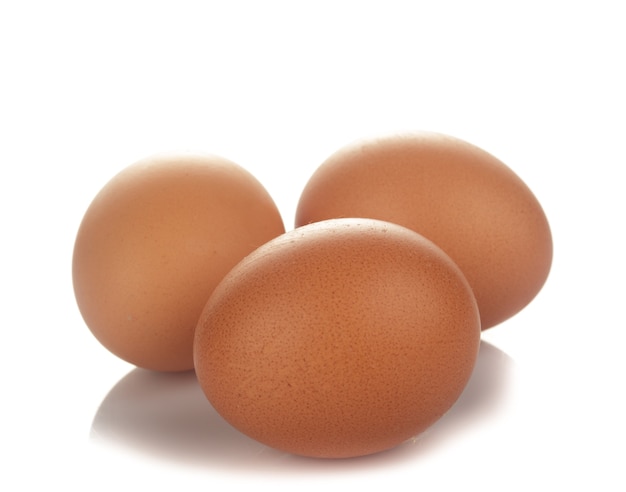 Tres huevos de gallina beige aislados en blanco