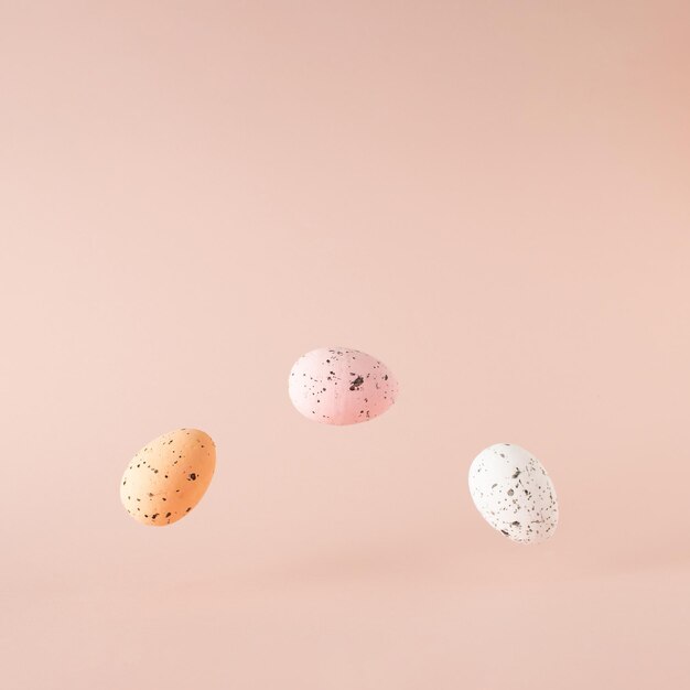 Tres huevos de Pascua en el aire sobre fondo rosa