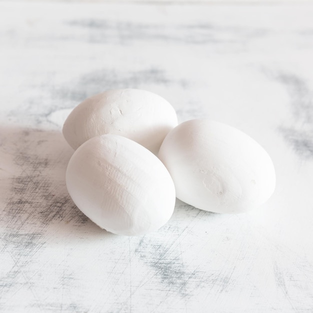 Tres huevos de Pascua blancos sobre un fondo vintage de madera blanca