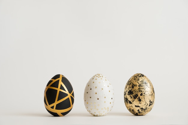 Tres huevos de Pascua decorados de oro. Minimo concepto de pascua