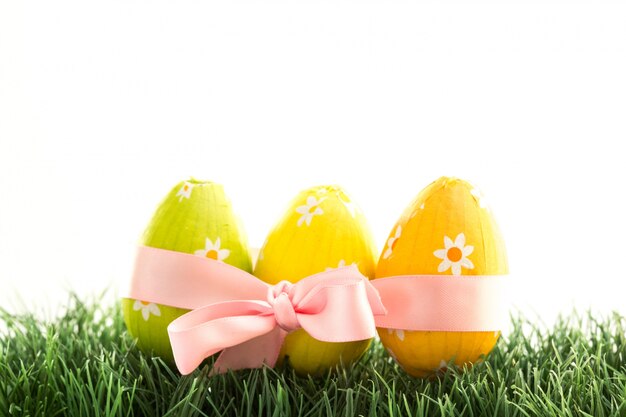 Tres huevos de Pascua envueltos en cinta rosa con un lazo