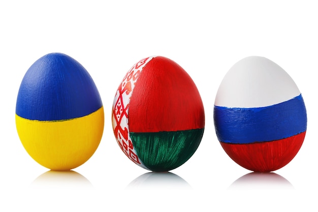 Tres huevos de Pascua pintados en los colores de las banderas de Ucrania, Bielorrusia y Rusia aislado sobre una superficie blanca