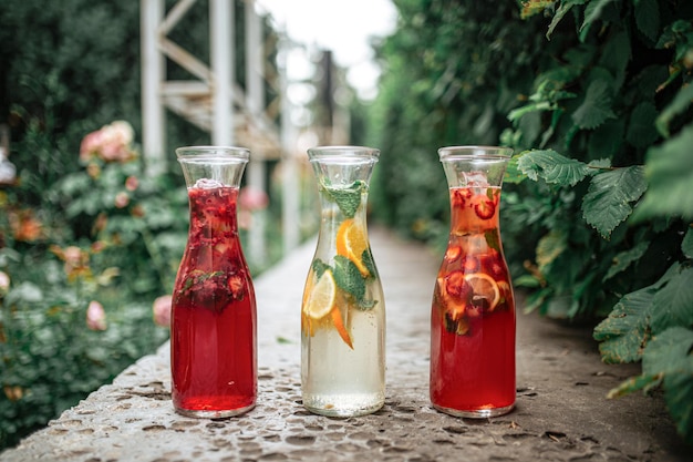 Tres jarras de vidrio de bayas frescas y limonada de frutas