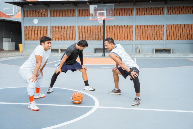 Três jogadores de basquete esticando as pernas durante o aquecimento antes de se exercitar