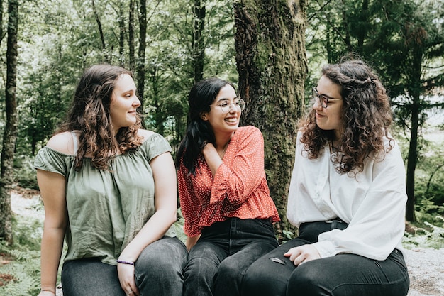 Tres joven conversando en el bosque durante un día soleado, afecto y amistad, sonrisas y cuidado