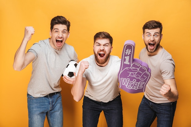 Foto tres jóvenes aficionados al fútbol entusiasmados celebrando