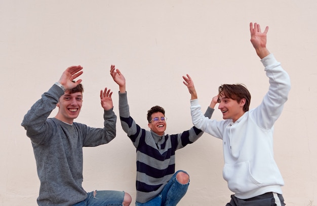 Tres jóvenes amigos alegres bailando y divirtiéndose en un fondo liso