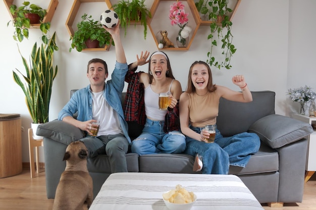 Tres jóvenes amigos alegres y gritando viendo un partido de fútbol