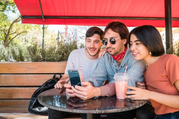 Tres jóvenes amigos tomando una selfie con teléfono.