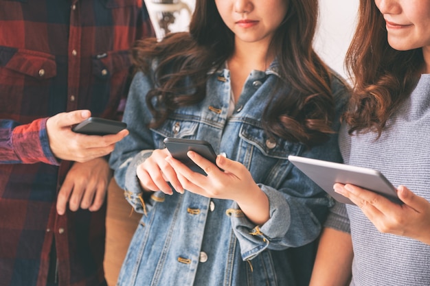 Tres jóvenes asiáticos que usan y miran juntos el teléfono móvil y la tableta