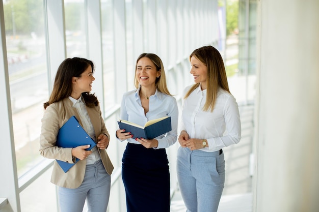 Tres jóvenes empresarias discutiendo mientras caminan por el pasillo de la oficina