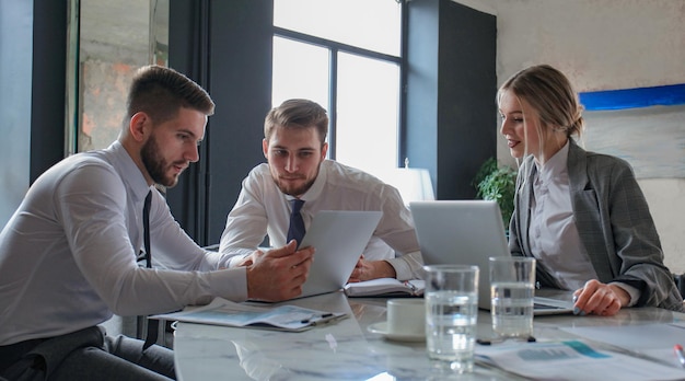 Tres jóvenes empresarios discutiendo negocios en una reunión de oficina