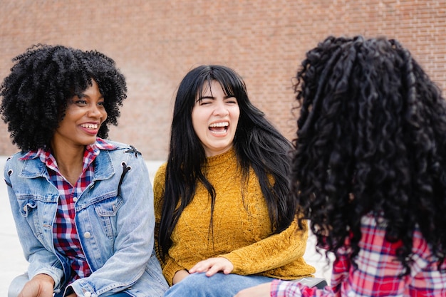 Tres jóvenes estudiantes de intercambio latinas riéndose juntas en el campus universitario