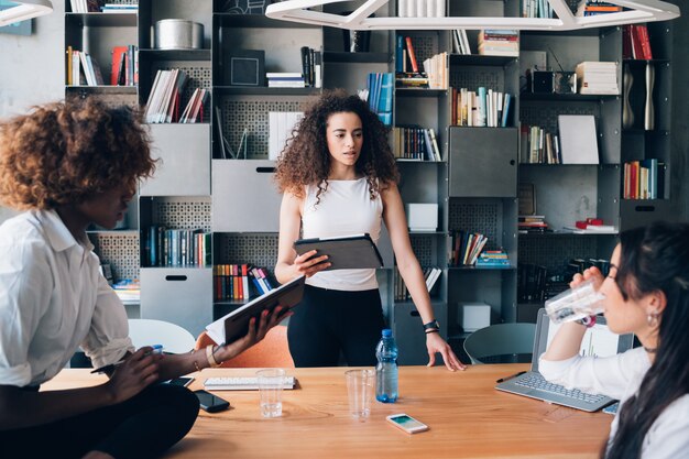 Foto tres jóvenes estudiantes multiculturales discutiendo proyecto en la oficina de coworking