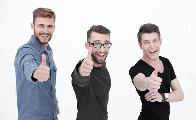 Foto tres jóvenes felices con thumbs up firman en casual aislado sobre fondo blanco.