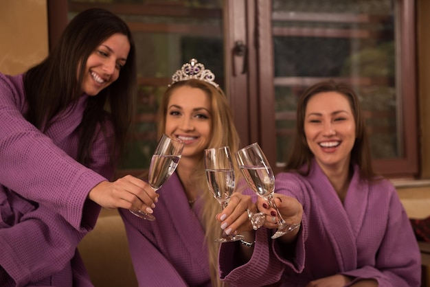 tres jóvenes hermosas chicas felices tienen una despedida de soltero en un spa de lujo con champán
