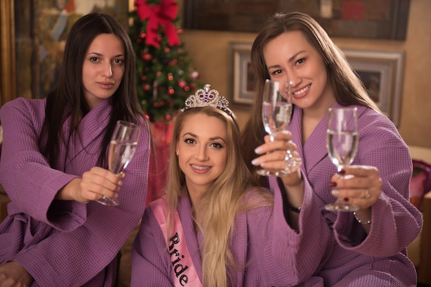 tres jóvenes hermosas chicas felices tienen una despedida de soltero en un spa de lujo con champán