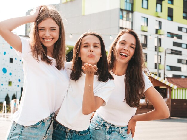 Tres jóvenes hermosas mujeres hipster sonrientes con la misma ropa de verano de moda Mujeres sexys y despreocupadas posando en el fondo de la calle Modelos positivos divirtiéndose Abrazando Alegre y feliz