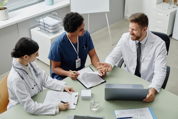 Tres jóvenes médicos reunidos en una mesa en la clínica.