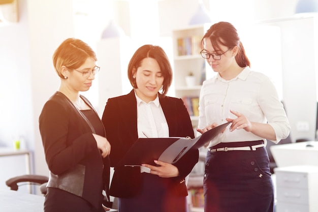 Tres jóvenes mujeres de negocios exitosas en la oficina trabajando juntas en un proyecto.