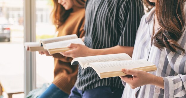 Tres jóvenes de pie y disfrutaron leyendo libros juntos.