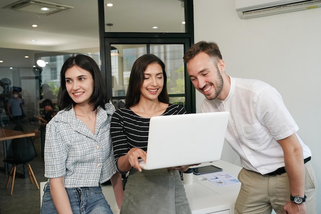 Tres jóvenes profesionales de negocios de pie juntos y discutiendo sobre el informe comercial