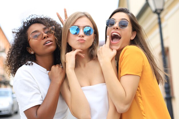 Tres jóvenes sonrientes hipster mujeres en ropa de verano posando en la calle. Mujer mostrando emociones positivas en la cara.