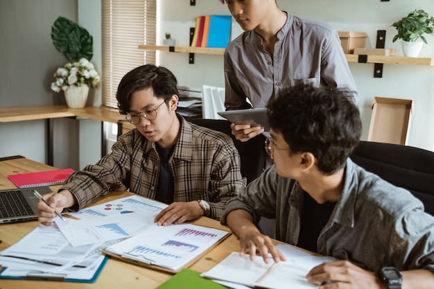 Tres jóvenes trabajadores asiáticos charlando sobre su producto