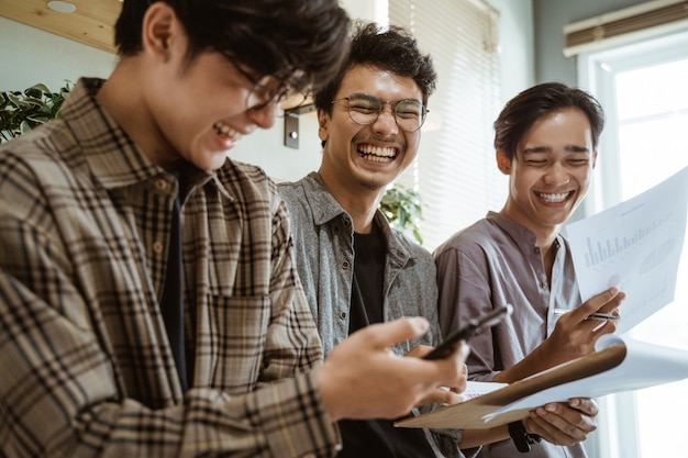 Tres jóvenes trabajadores asiáticos charlando sobre su producto