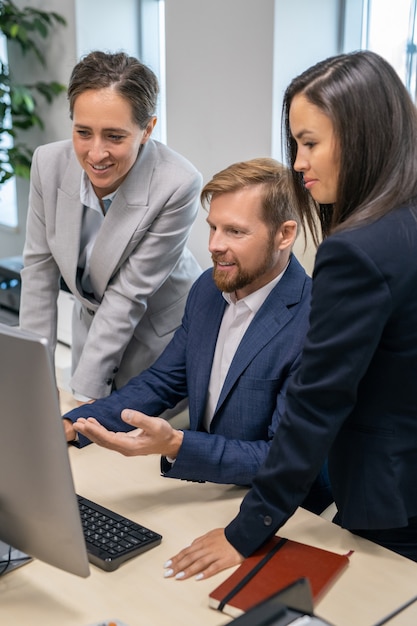 Tres jóvenes trabajadores de oficina mirando la pantalla del ordenador