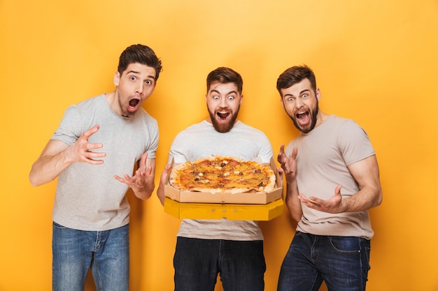 Três jovens alegres segurando uma pizza grande