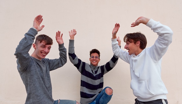 Três jovens amigos alegres dançando e se divertindo em um fundo simples