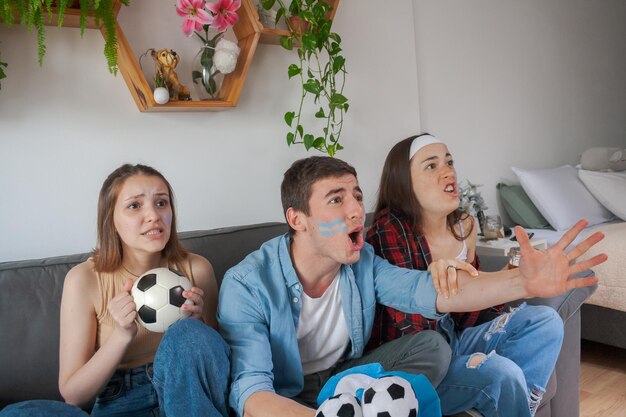 Três jovens amigos irritados e frustrados assistindo futebol