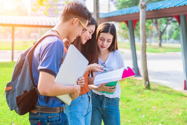 Três jovens asiáticos jovens do campus de tutoria e preparando-se para exame final na universidade