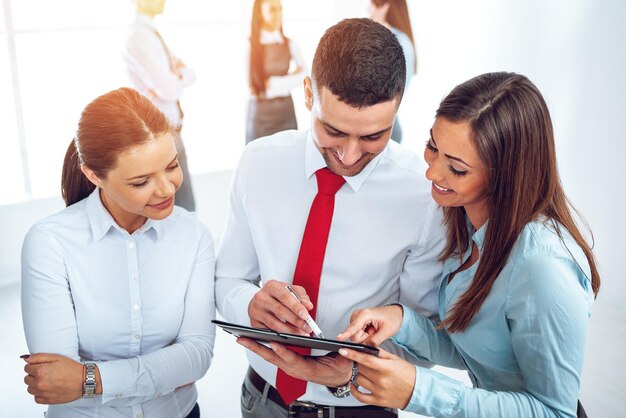 Três jovens colegas sorridentes discutindo na frente de sua equipe de negócios.