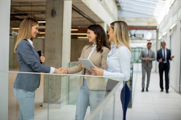 Três jovens empresárias discutindo no corredor do escritório