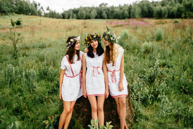 Três jovens étnicas em vestidos brancos, posando no campo.