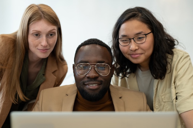 Foto três jovens funcionários felizes olhando para a tela do laptop