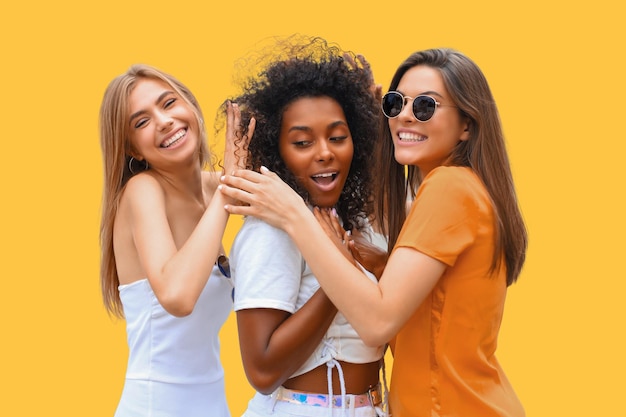 Foto três jovens hipsters sorridente em roupas de verão posando em fundo amarelo mulher mostrando emoções faciais positivas