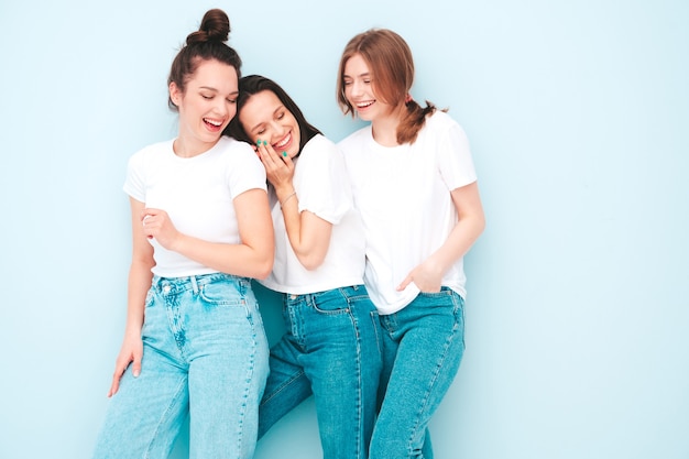 Três jovens lindas e sorridentes mulheres hippie no mesmo verão, camiseta branca e roupas jeans