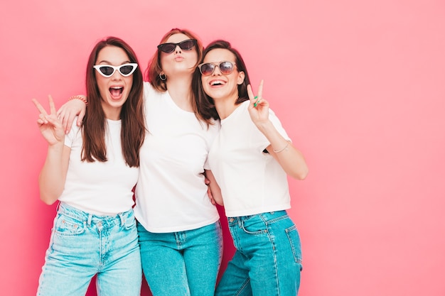 Foto três jovens lindas e sorridentes mulheres hippie no mesmo verão, camiseta branca e roupas jeans